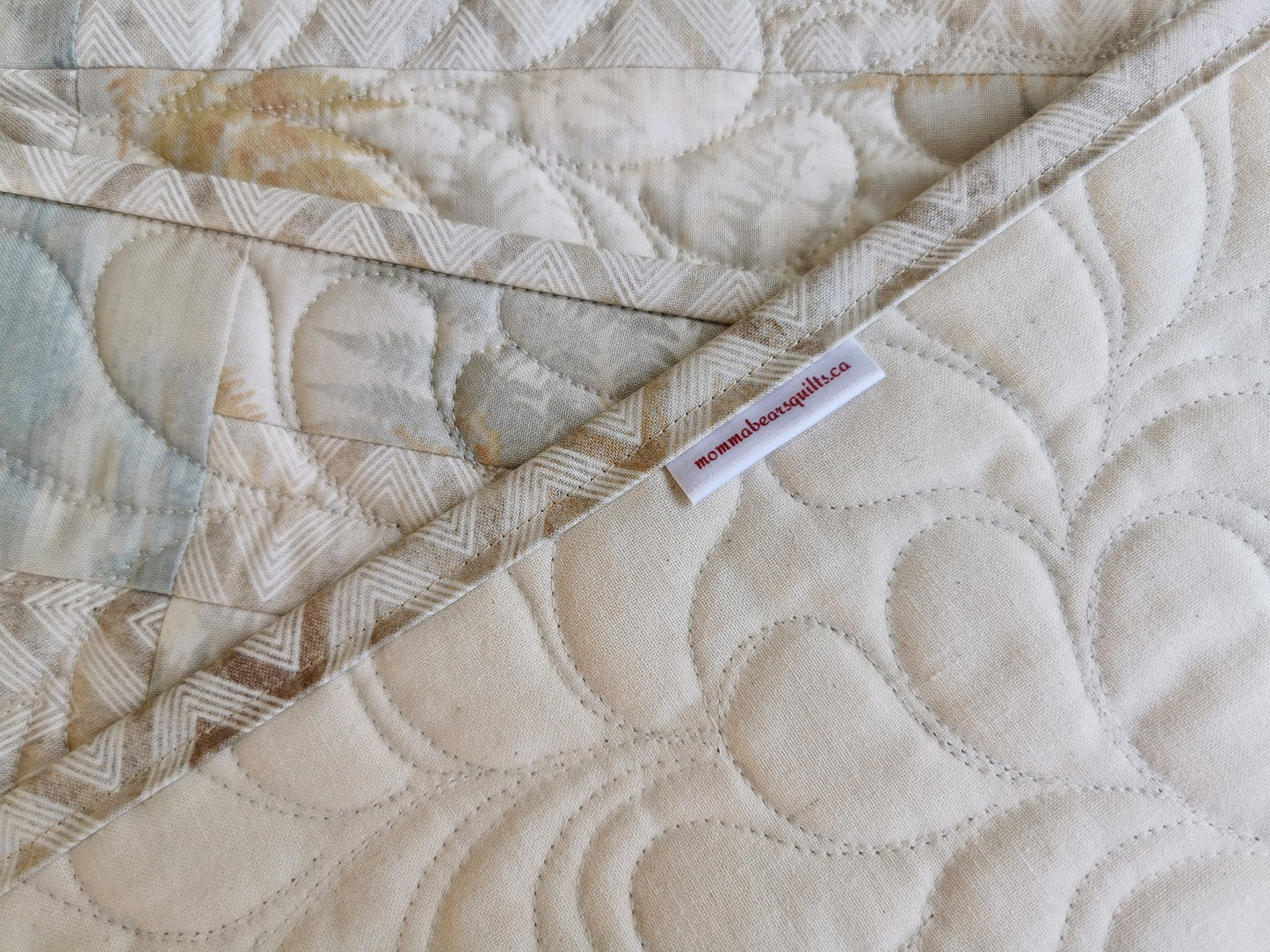 The quilted placemats have a plain ecru muslin  for the backing, shown here. Freehand feather quilting detail is also visible, in this close up.