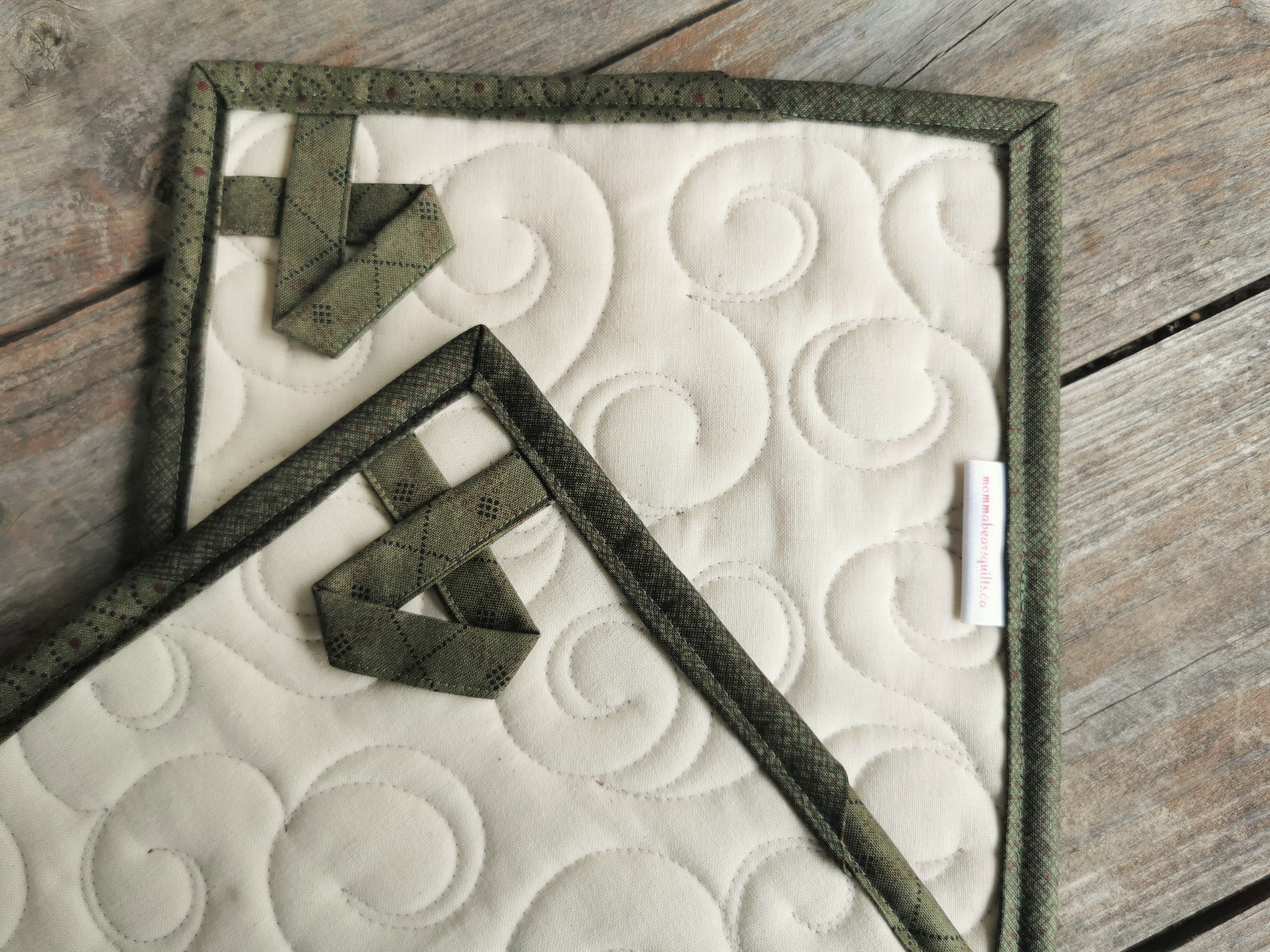 The back of the quilted patchwork potholders feature hanging loops and muslin backing that shows the swirl quilting nicely. 