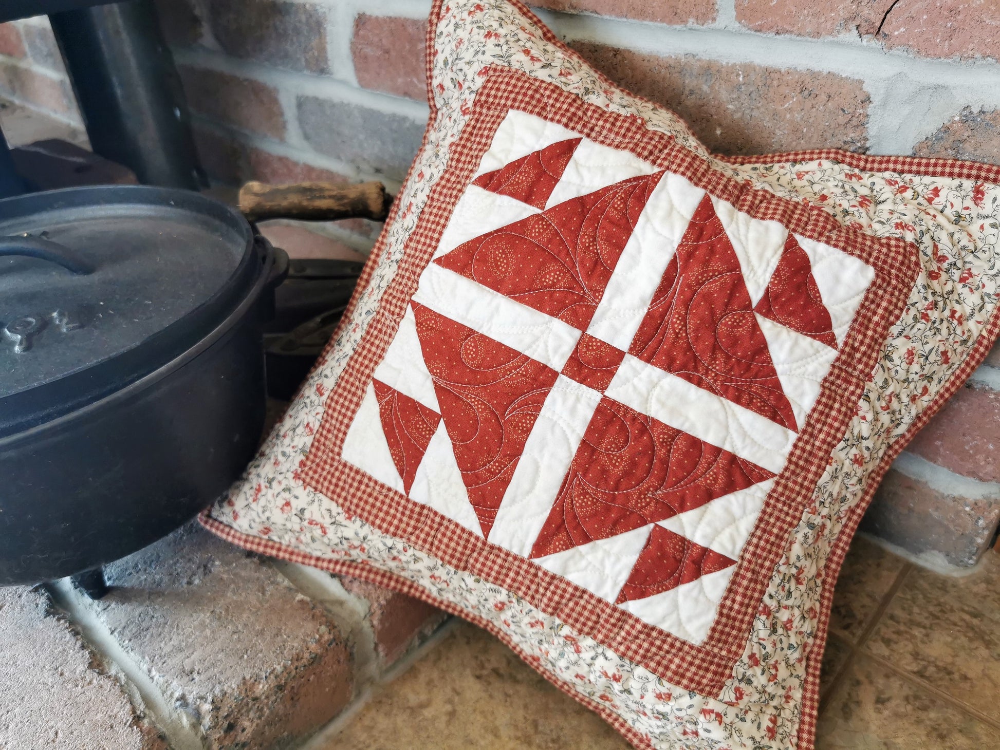 This pretty red and cream quilted pillow has a lovely country feel. Red and white center piecing is set off by a red gingham border. Finished with a cream and red floral fabric for the outer border, it is a pretty addition to your decor.