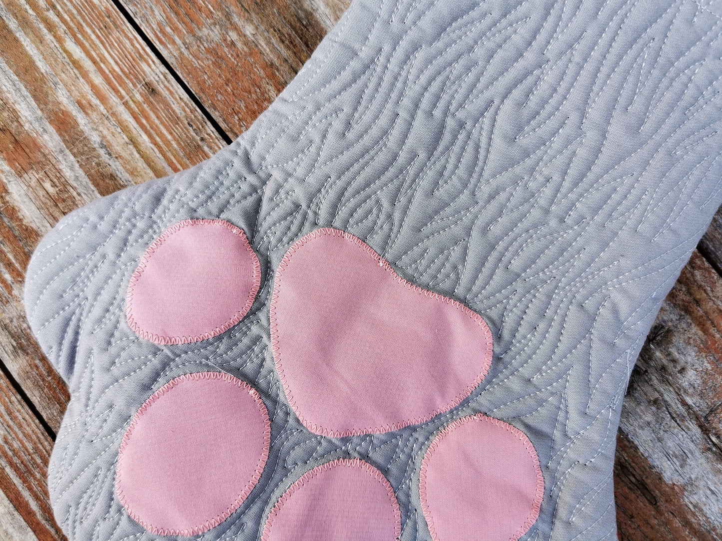 close up view of grey pet stocking showing fur like quilting and pink toes