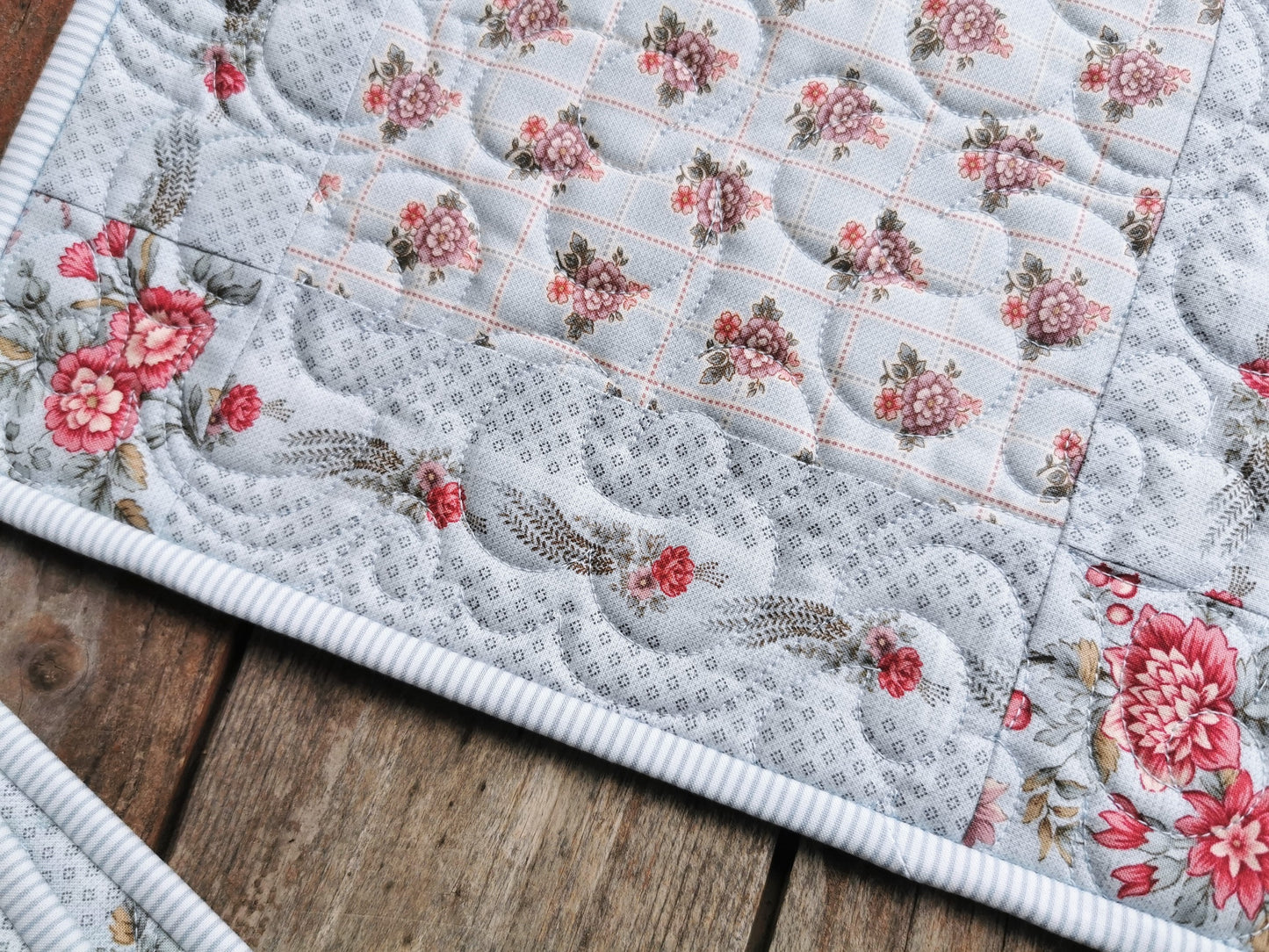 Super close up view shows the detail of the beautiful french floral fabrics, pale blue background and pinstripe binding. Workmanship and quilting is also displayed prominently.