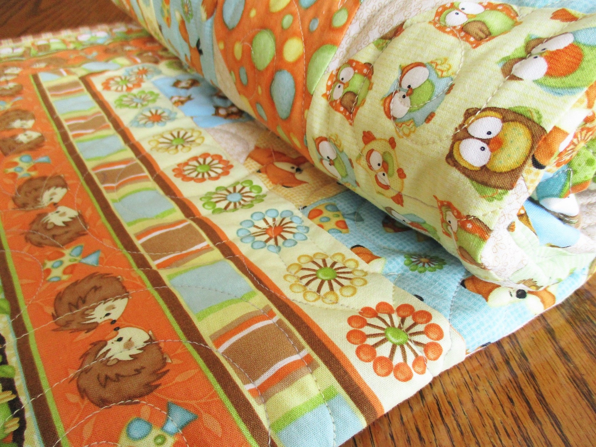 woodland animals adorn this sweet baby quilt. quality cotton fabrics, in gender neutral brown orange blue yellow green 