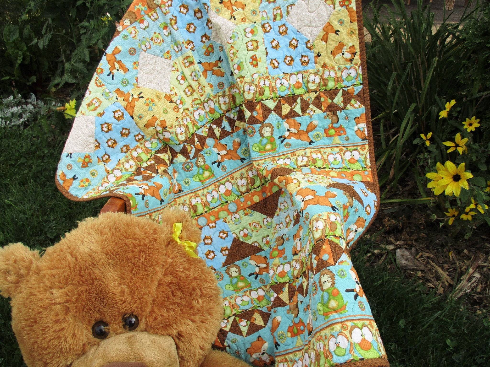 This improv, scrappy baby quilt features little animals and gender neutral colors in blue, green, orange, brown, yellow.