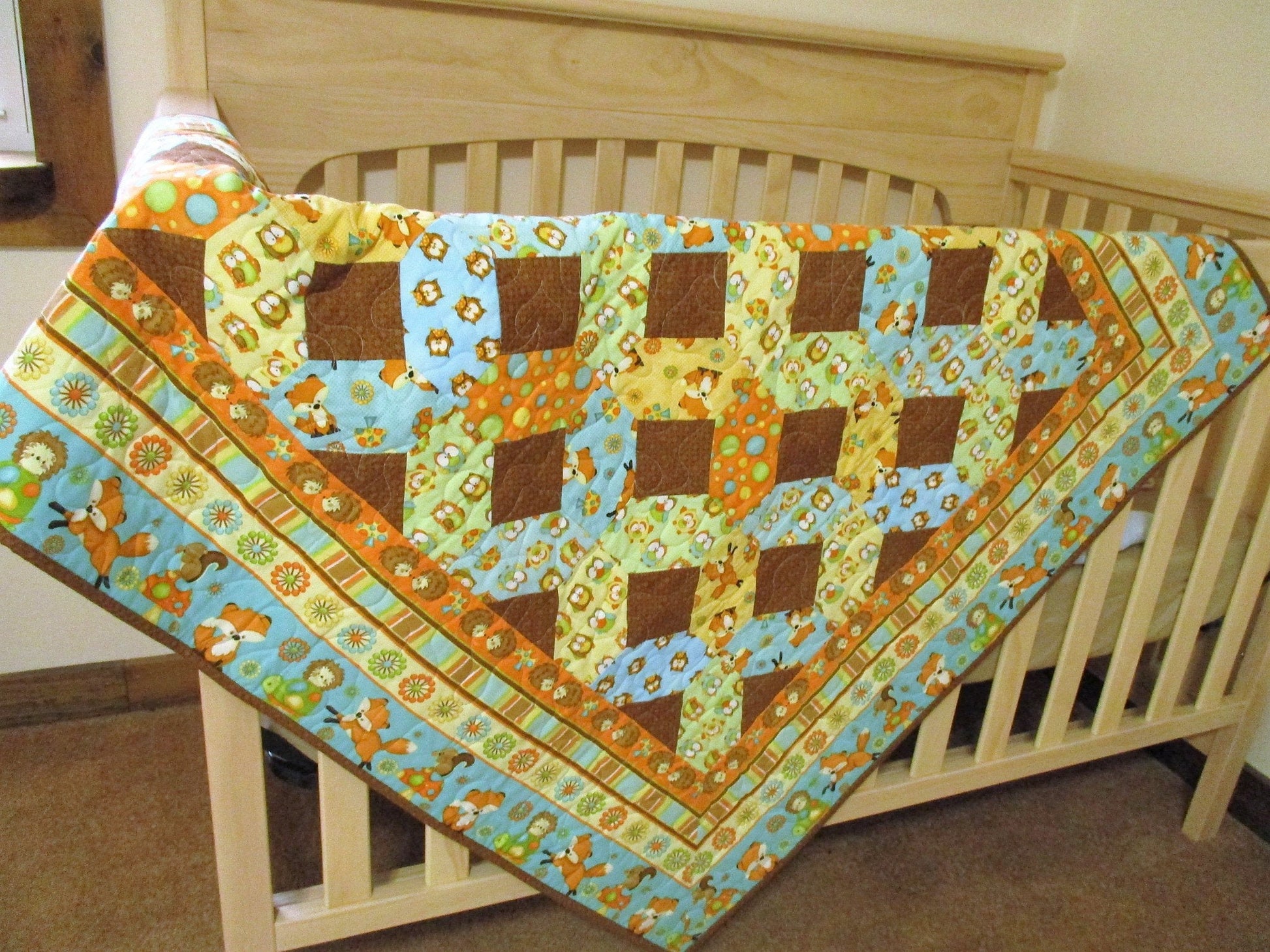 showing the woodland quilt draped over the side of a crib, showing scale