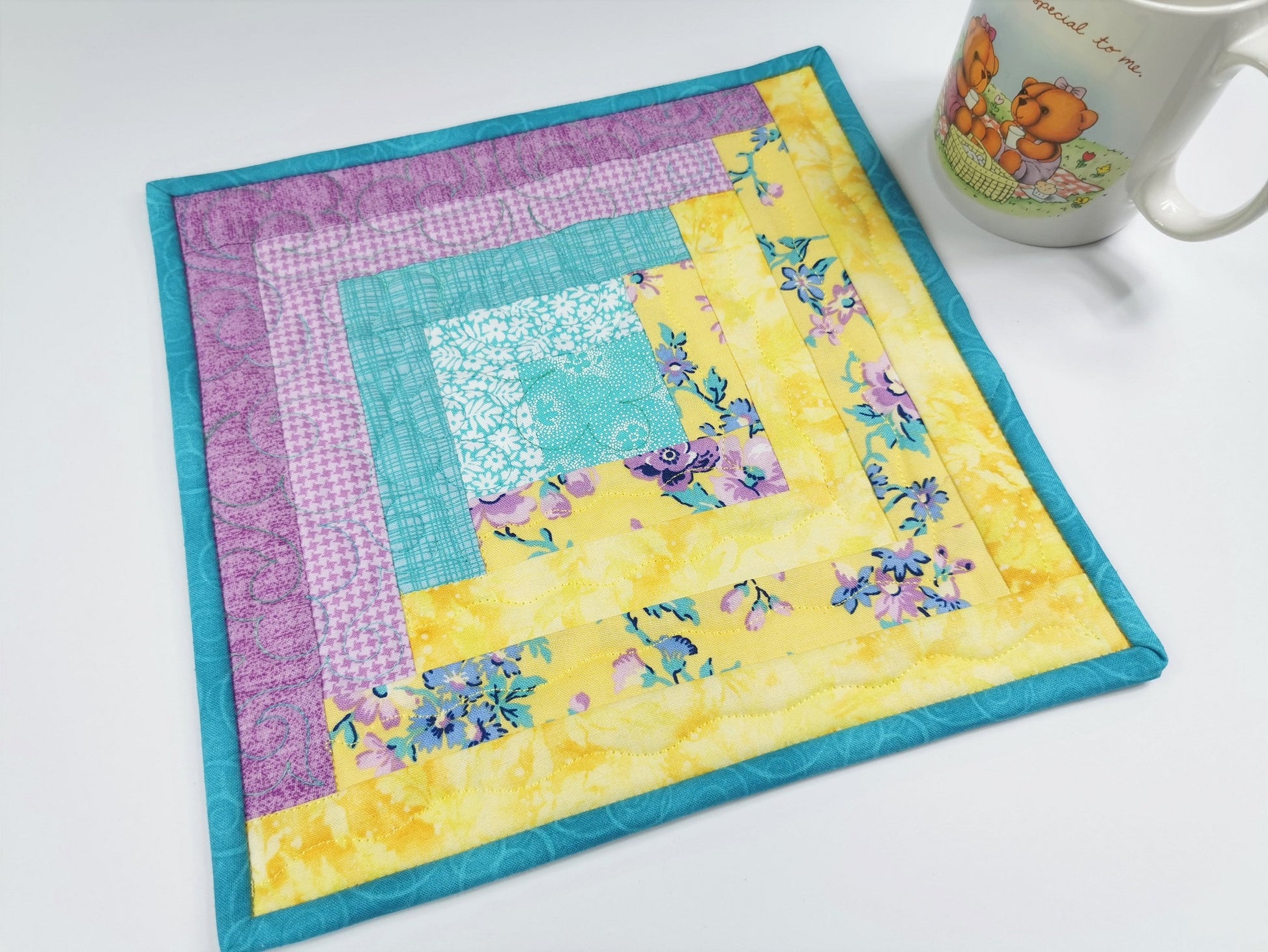 This quilted mug rug feels like Easter and spring. Yellow, teal and light purple fabrics are pretty together.