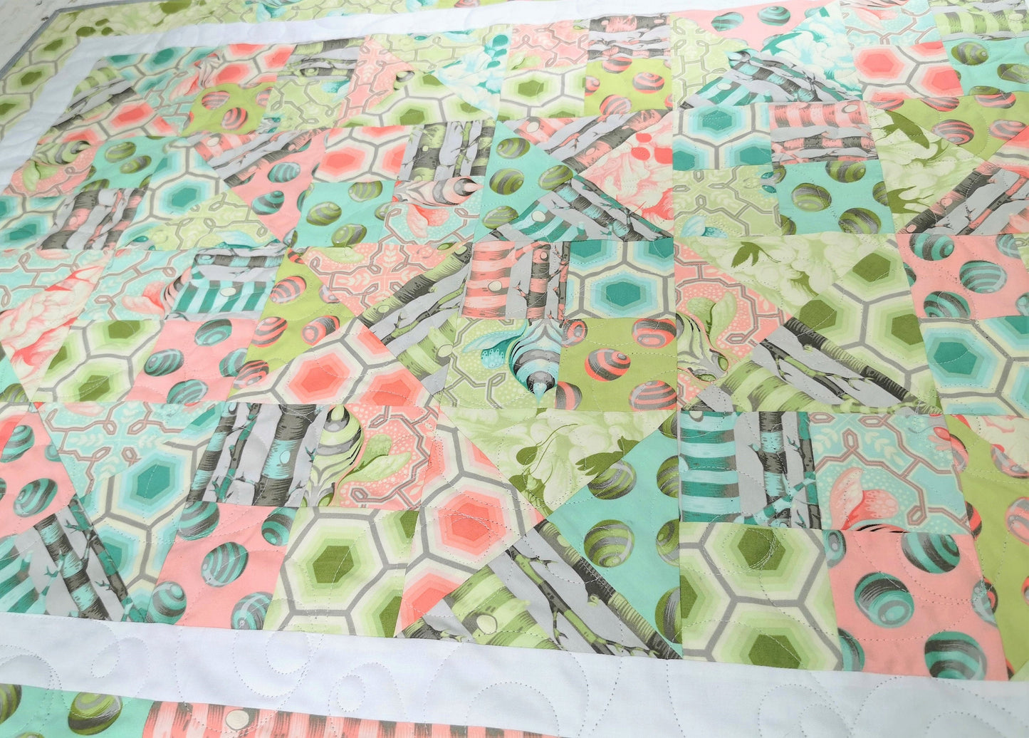 Soft pastel colors and fanciful bee themed fabrics give this baby quilt a Dr. Suess feel. 