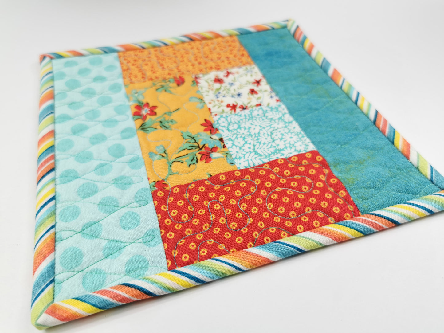 This cheerful quilted mug rug has bright summery colors of teal, white, orange, red.