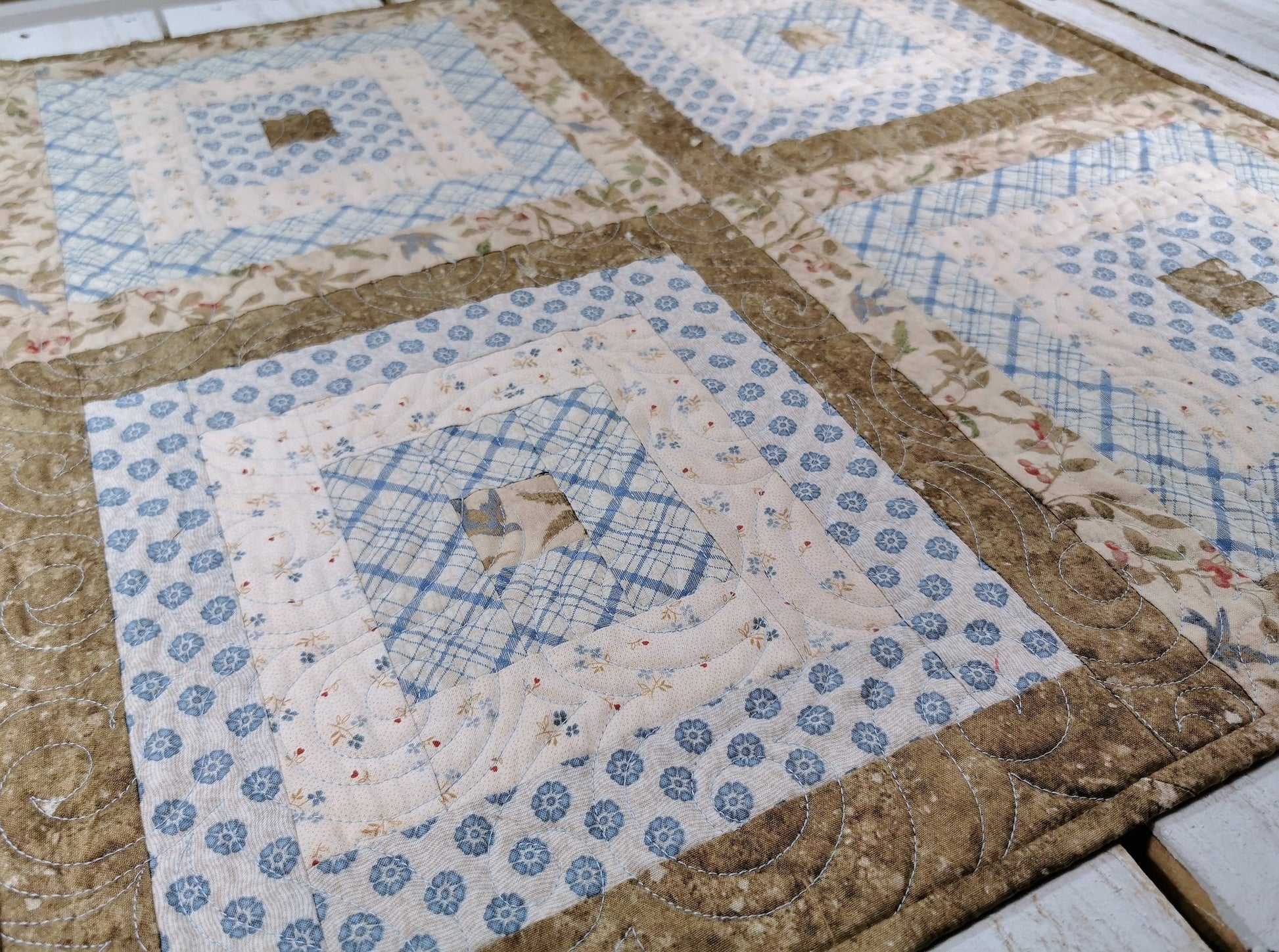 Angle view of the square table topper showing a close up of the blue and beige fabrics used