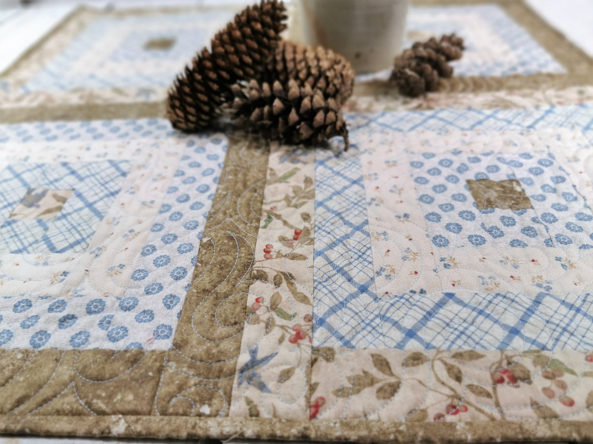close up of quilt with pinecones in the background showing scale