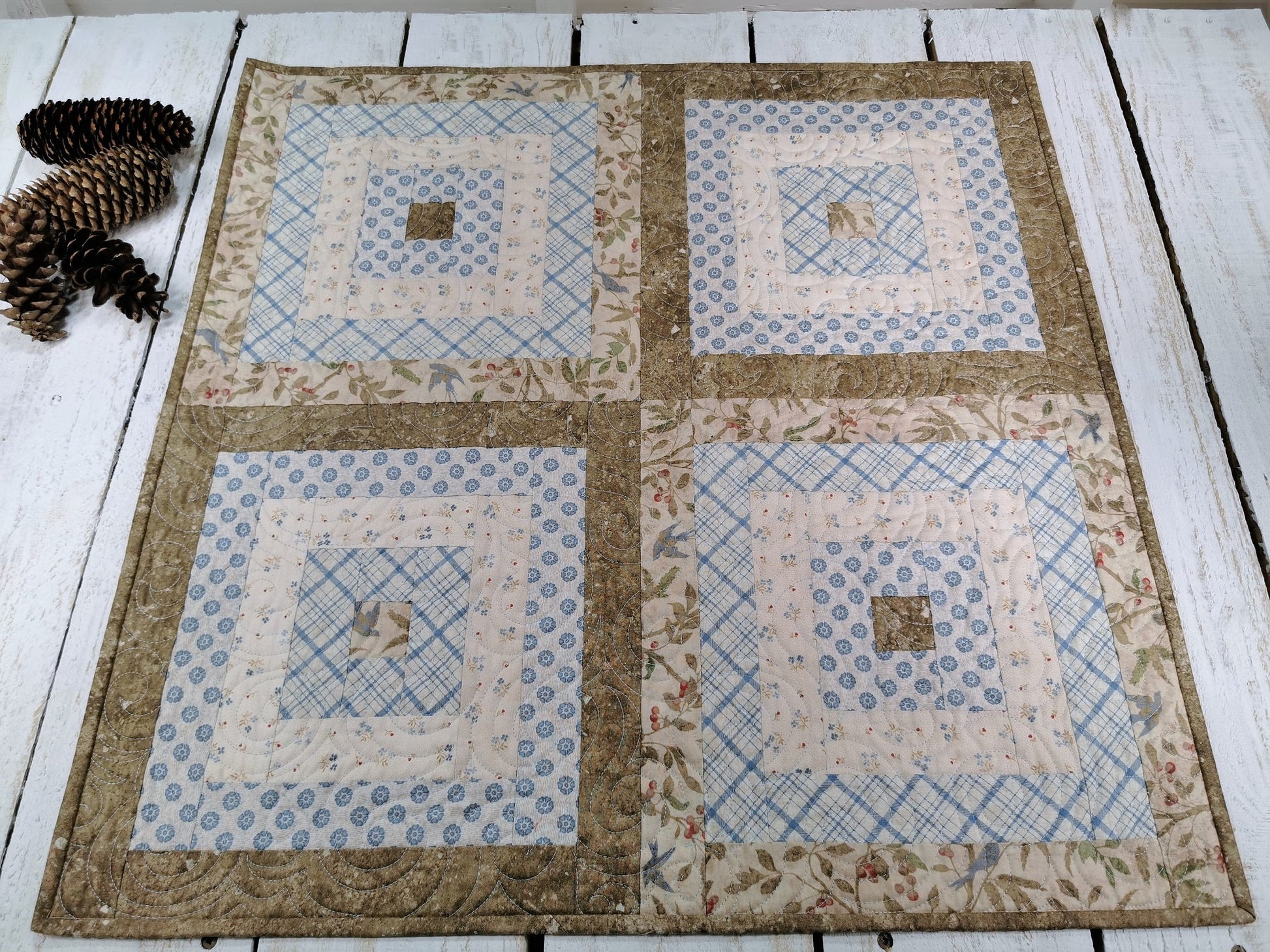 showing full view of the table topper on a white wooden table with pinecones beside.