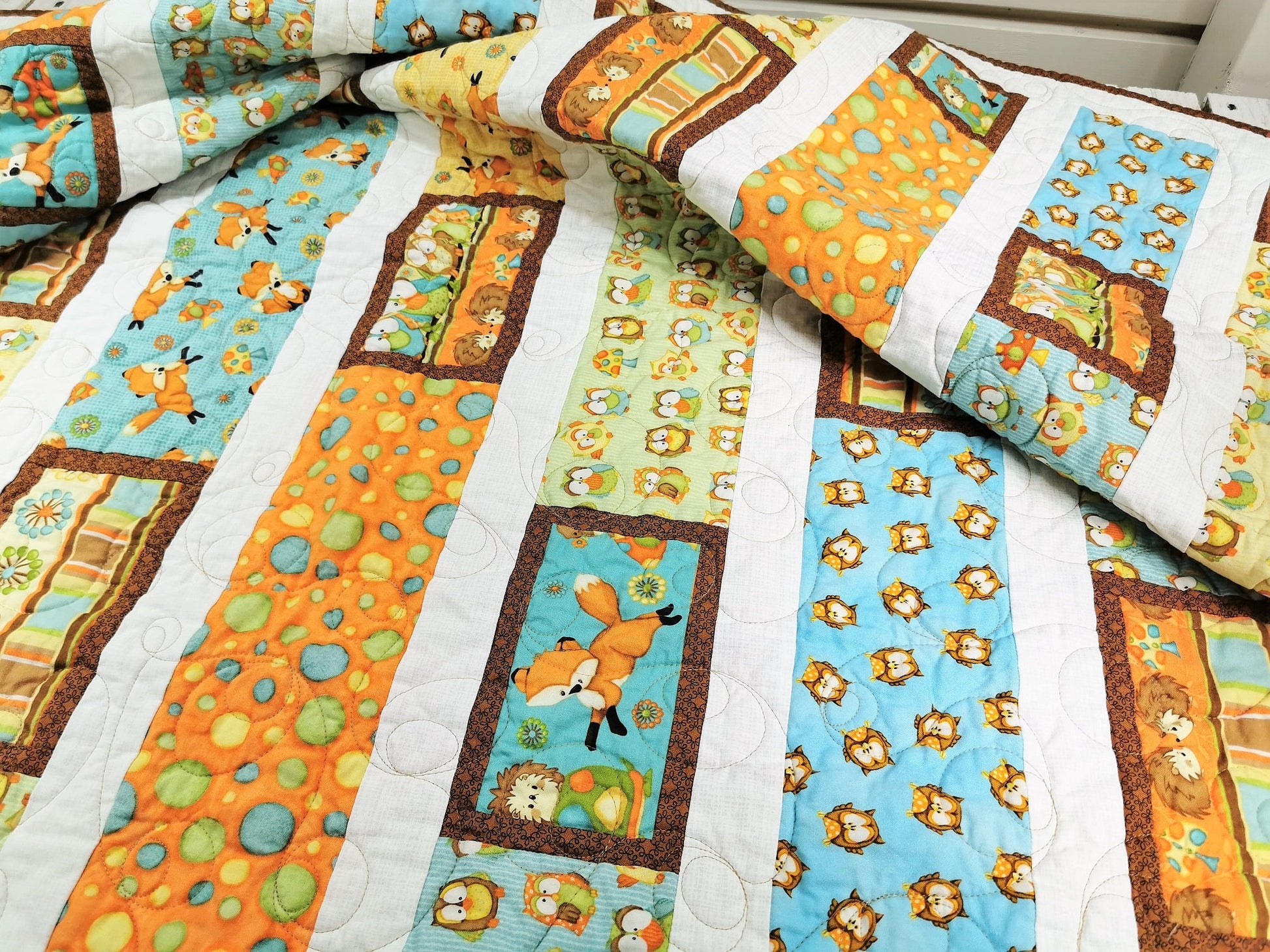 This modern toddler quilt has colorful stripes of cute animal fabric. See Owls, foxes, hedgehogs, mushrooms, dots, and more