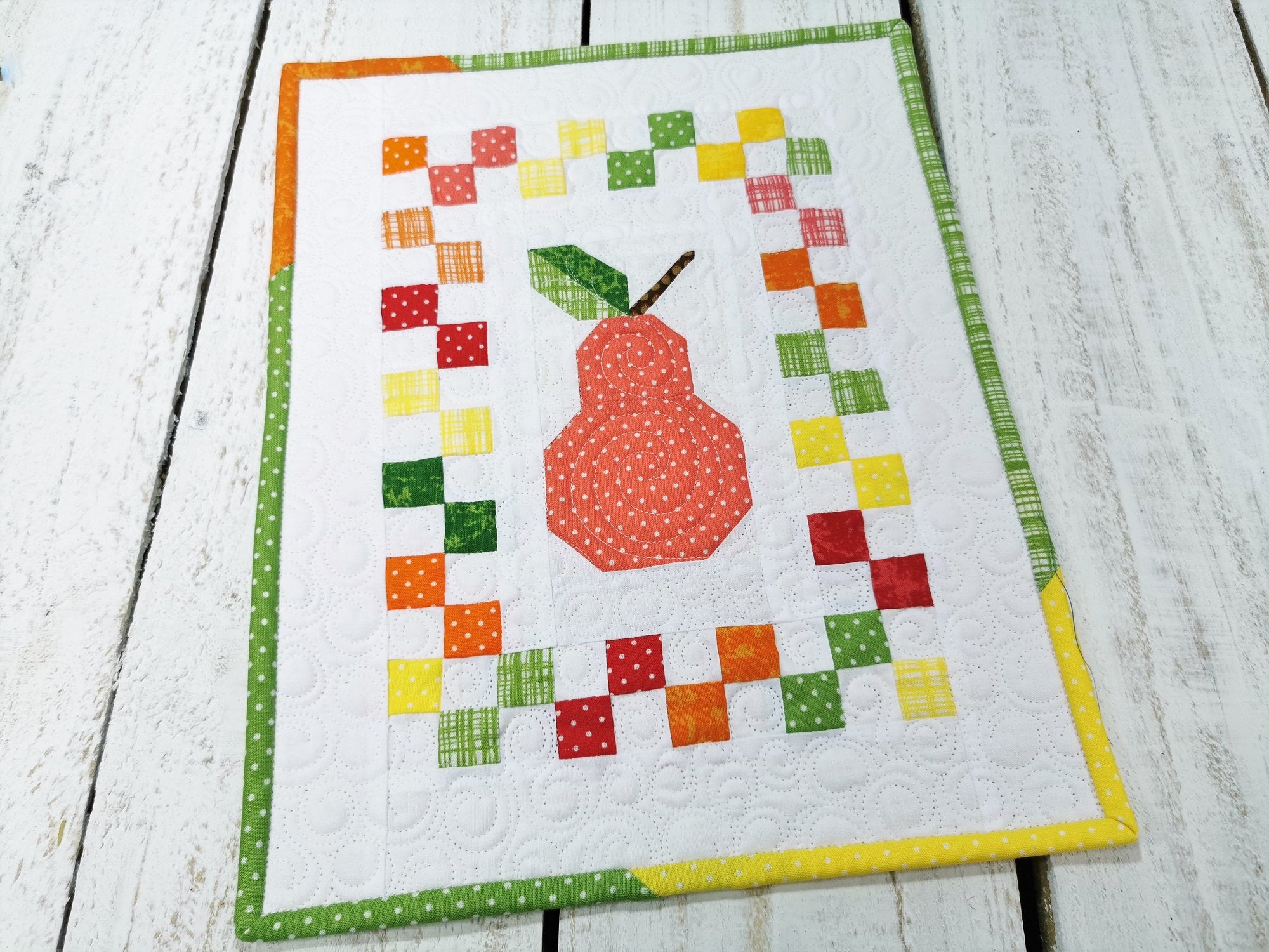 This improv patchwork pear quilt is perfect for decorating. Bright and colorful it is perfect for summer. Colors include yellow, green, orange, red, coral on a white background. Custom quilting adds beautiful detail. One-of-a-kind!