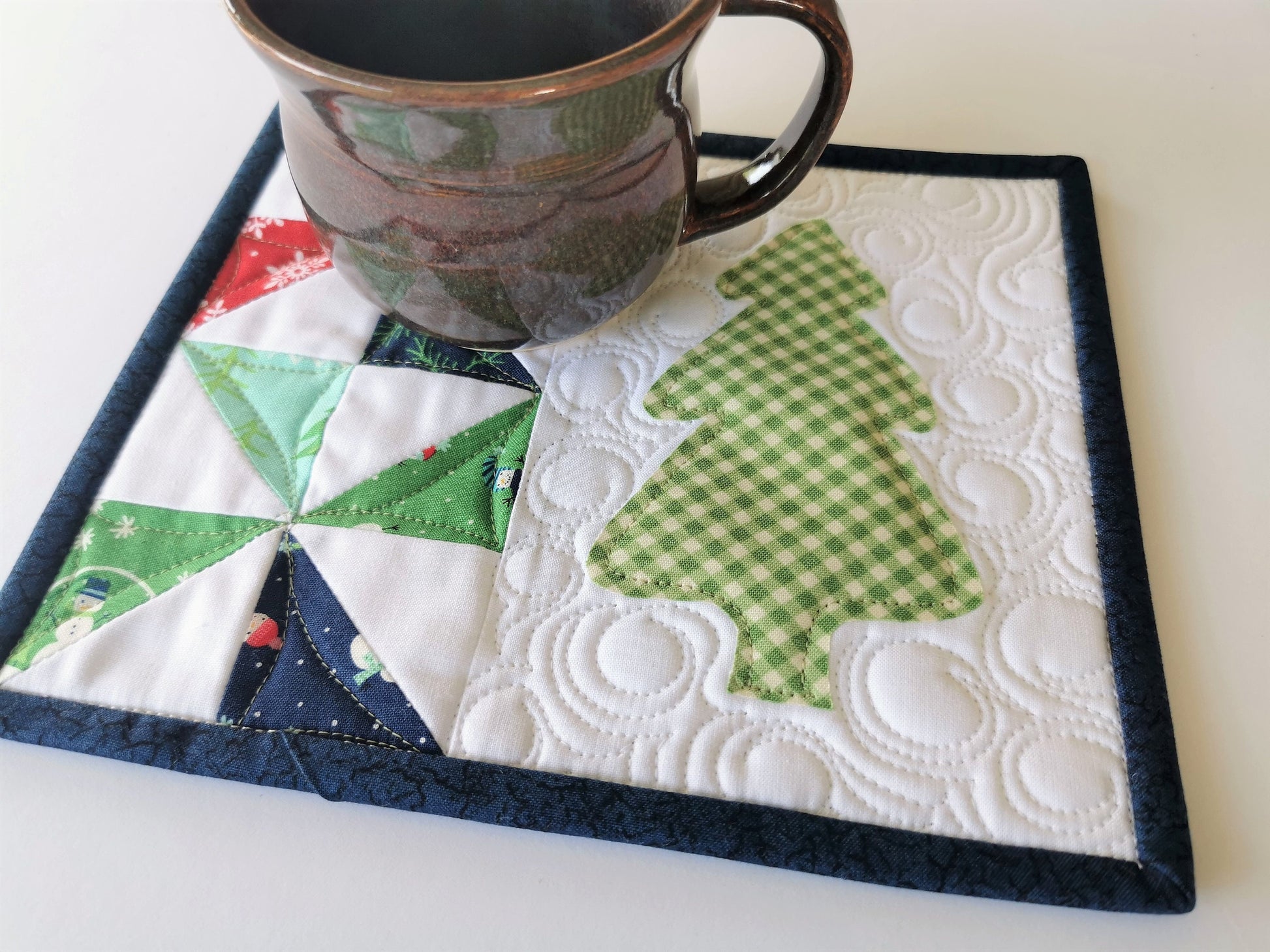 large quilted coaster with green gingham evergreen tree and scrappy patchwork pinwheel in winter theme fabrics