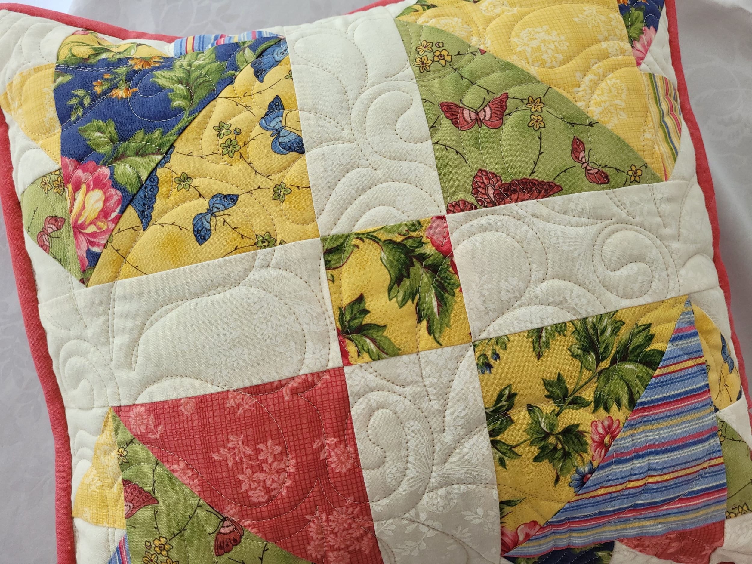 yellow, green, pink and blue floral prints are featured in this patchwork bear paw pillow