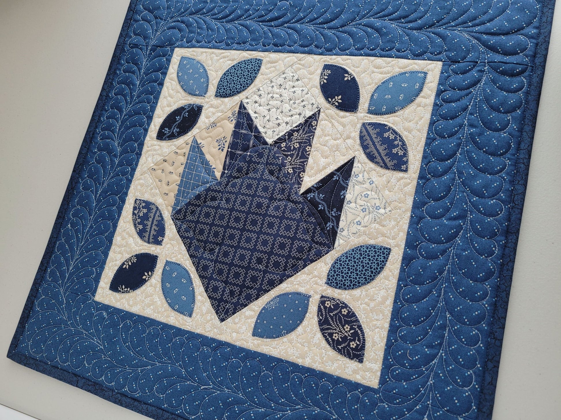 blue wall quilt with applique leaves and bear paw patchwork