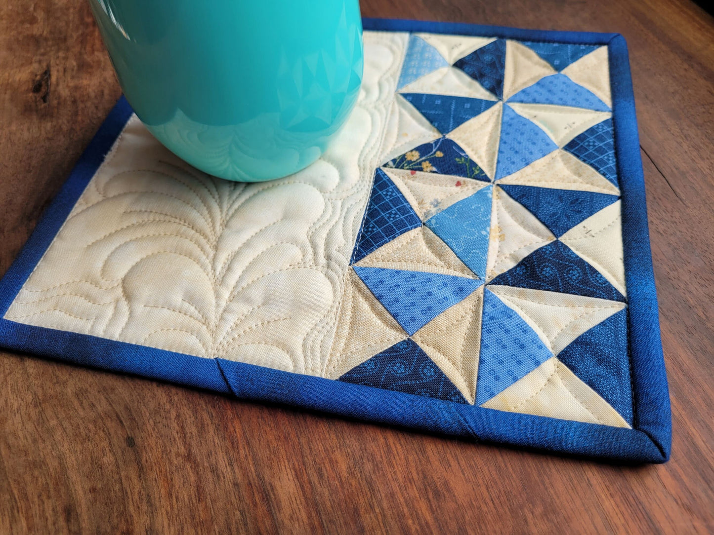 blue patchwork mini quilt with dark binding and feather quilting